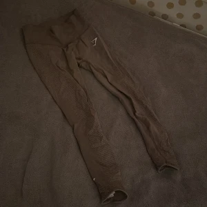 Träningstights från Gymshark med scrunch - Snygga bruna/beiga leggings från Gymshark i storlek S. Perfekta för träning med en tight passform och diskret logga på benet. De har scrunch där bak som ger en snygg form. Nytvättade.
