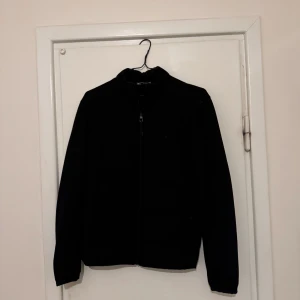 Svart jacka med dragkedja - Säljer en stilren svart jacka med dragkedja. Jackan har en enkel design med långa ärmar och en normal passform. Sitter riktigt bra på kroppen stolen M sitter även bra på storlek S, pris kan diskuteras 