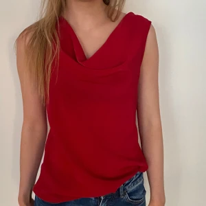 Röd ärmlös topp - Snygg röd ärmlös topp med draperad halsringning. Perfekt för en night out eller middag. Passar även flera storlekar beroende på hur man vill att den sitter!💃