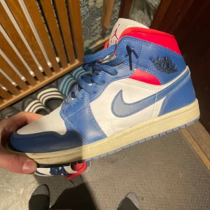 Nike Air Jordans i blått, vitt och rött - Snygga Nike Air Jordans i en fräsch färgkombination av blått, vitt och rött. Skorna har klassisk snörning och den ikoniska Air Jordan-loggan på sidan. Perfekta för dig som vill ha en stilren och sportig look. Priset är ej hugget i sten om ni har frågor är det bara att kontakta mig☺️