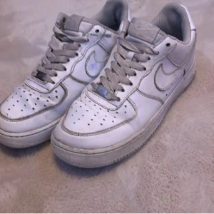 Vita Nike Air Force sneakers - Helt äkta vita välanvända airforce 1 i storleken 42 men passar 41,1/2 och 42,1/2 Nypris 1700 på merch sweden och säljs för endast 199kr eftersom de har defekter och små hål under sulan vid hälen men även lite skrift och målarfärg. Tveka inte att fråga😊