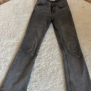 Grå jeans från Gina Tricot - Snygga grå jeans från Gina Tricot i en klassisk straight fit. De är tillverkade av mer hållbar bomull och har en stilren design med fem fickor och knappgylf. Perfekta för en avslappnad look.