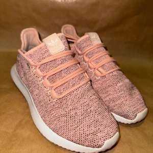 Rosa sneakers från Adidas - Snygga rosa sneakers från Adidas med stickad ovandel och vit sula. Skorna har snörning och en bekväm passform, perfekta för vardagsbruk. Den stickade designen ger en modern och luftig känsla. Storlek 39