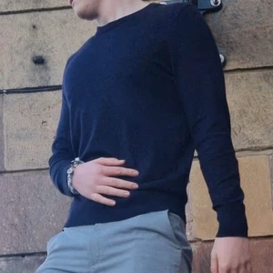 Mörkblå tröja - Säljer en stilren mörkblå tröja med långa ärmar. Perfekt för en avslappnad och snygg look. Passar bra till både jeans och chinos. Dissefekt är på sista sidan. Ett litet hål som knappt syns