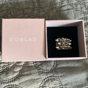 Silverfärgad ring från Edblad - Säljer en snygg och modern silverfärgad ring från Edblad i storlek 16,80💗. Ringen har en unik design med små pyramidformade detaljer som ger den en cool och edgy look. Perfekt för att piffa upp vilken outfit som helst! 