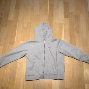 Lacoste grå zip hoddie. Pris kan diskuteras! Stl 164/XS - Lacoste grå zip hoddie. Pris kan diskuteras! Stl 164/XS