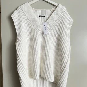 Vit stickad väst från Gina Tricot - Säljer en superfin vit stickad väst från Gina Tricot. Den har en snygg v-ringad design och är perfekt för lager-på-lager under höst och vinter. Västen är i nyskick och passar perfekt för en stilren look.