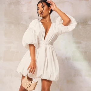 Vit kortklänning med puffärmar - Säljer en superfin vit kortklänning med puffiga ärmar och v-ringning. Klänningen har en elastisk midja som ger en snygg passform. Materialet känns lätt och luftigt. Perfekt för en chic och stilren look! 🤍