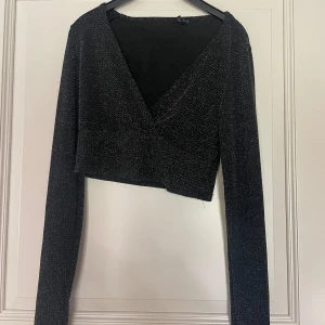 Svart-glittrig långärmad topp - Croppad svart-glittrig långärmad topp ifrån new yorker. aldrig använd, Storlek m, men passar mig som har s och passar troligen större med då den är rätt stretchig