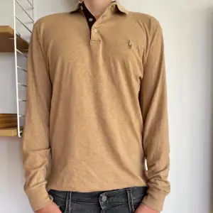 Långärmad polo Ralph lauren tröja i storlek S! Den är köpt på zalando och är i färgen ”Camel” den är i superbra skick och nypriset är 1800kr!  Den har en liten svart prick på vänstra armen men inget märkvärdigt, Hör av er vid frågor! Svarar snabbt!