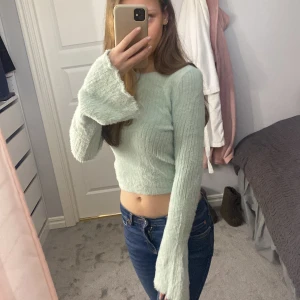 ribbad tröja - Säljer en ljusgrön ribbad tröja med långa ärmar och en croppad passform. Tröjan har en mysig och mjuk känsla, perfekt för en avslappnad stil. Passar bra till jeans eller kjol.