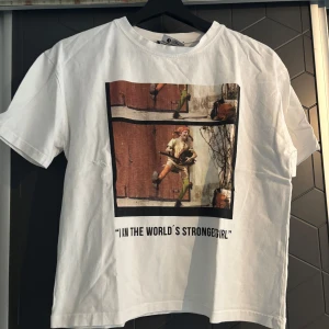 Vit t-shirt med Pippi Långstrump-tryck - Säljer en vit t-shirt från Zara med ett coolt Pippi Långstrump-tryck på framsidan och text på baksidan. T-shirten har korta ärmar och en avslappnad passform. Perfekt för alla Pippi-fans! 🌟
