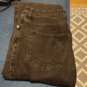 Svarta bootcut jeans från &Denim - Snygga svarta bootcut jeans från &Denim i storlek 38. De har en hög midja och klassisk femficksdesign med dragkedja och knapp framtill. Perfekta för en stilren look.