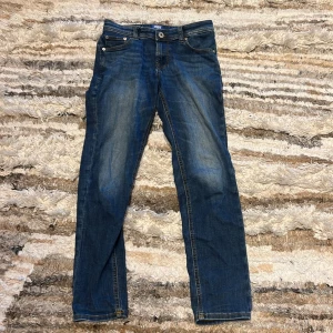 Blå jeansbyxor för ungdomar - Snygga blå jeansbyxor i slim fit för ungdomar. De har en klassisk femficksdesign och en knappgylf. Perfekta för en avslappnad stil. Storlek 12 y/ 152