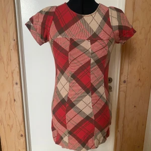 Rutig klänning med korta ärmar - Trendig rutig klänning i rött, beige och brunt med korta puffärmar. Den är i storlek xs och är väldigt kort så jag som är 180 har använt den som en tröja men om man är kortare kanske det går att ha som klänning. Väldigt fin iaf.