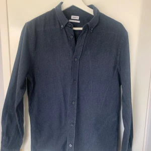 Mörkblå skjorta från Filippa K - Snygg mörkblå skjorta från Filippa K med klassisk krage och knappar framtill. Perfekt för en stilren look. Skjortan har långa ärmar och är tillverkad i ett mjukt material.