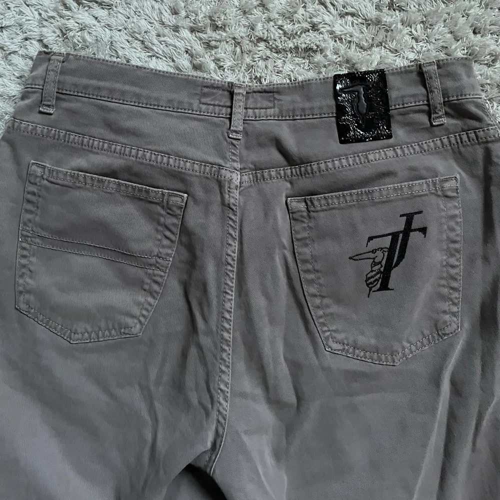 Snygga grå byxor från Trussardi Jeans med en klassisk femficksdesign. Byxorna har en normal passform och är tillverkade i ett bekvämt material. Perfekta för en stilren look. Jag skulle säga storlek M, men kanske något större M. 32 i längd💞. Farkut & Housut.