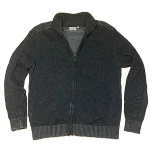 Grå stickad kofta från Bexleys - Säljer en mörgrå stickad full-zip kofta från Bexleys. Storleken är S och skicket är helt okej med tanke på slitage i ärmar och öppning i tröjan samt vid dragkedjan. 