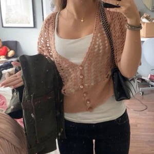 Rosa stickad kofta med knappar - sommar25 - Säljer en rosa stickad kofta med korta ärmar och knappar framtill. Perfekt för lager-på-lager och ger en avslappnad look. Passar bra till både jeans och klänningar.