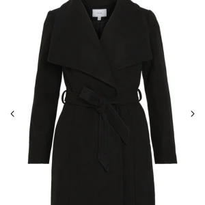 Svart kappa från Vila - Elegant svart kappa från Vila med knytbälte i midjan och bred krage. Jätte fin till vår🫶(kom privat för egna bilder)