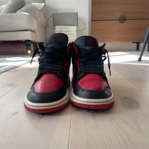 Nike Air Jordans i svart och rött - Säljer ett par klassiska Nike Air Jordans i svart och rött. Skorna har en ikonisk design med snörning och en hög siluett. Perfekta för sneakerheads som älskar retrostil.