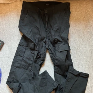 Svarta cargobyxor från lager157 - Snygga svarta cargobyxor från lager157 i storlek XS. Byxorna har flera praktiska fickor och är tillverkade i en bomullsblandning. Perfekta för en avslappnad stil.