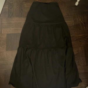 Svart långkjol - Elegant svart långkjol med volanger. Perfekt för en stilren look. 