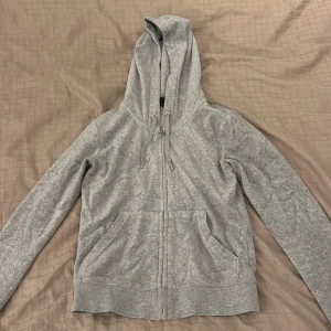 Grå hoodie från Juicy Couture - Säljer en stilren grå hoodie från Juicy Couture. Den har en dragkedja framtill och praktiska fickor. Perfekt för en avslappnad look. Huvan har dragsko för justerbar passform. Super fin och dunder skön. Finns byxorna också som jag kan sälja i storlek xs också.