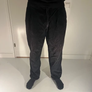 Svarta manchesterbyxor från Wampum - Snygga svarta manchesterbyxor från Wampum med hög midja. Byxorna har en klassisk rak passform och är perfekta för en stilren look. De är tillverkade i mjukt manchestertyg som ger en skön känsla.