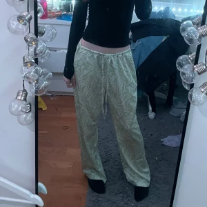 Gröna mönstrade byxor från ASOS Design - Snygga gröna byxor med ett subtilt mönster från ASOS Design. Byxorna har en loose passform och elastisk midja för extra komfort. Perfekta för en avslappnad stil.