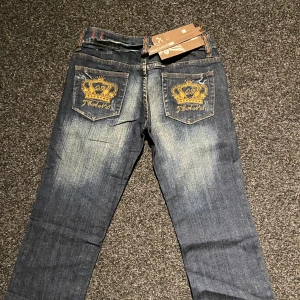 Blå jeans med broderad krona - Snygga blå jeans med unikt broderi av en guldkrona på bakfickorna. Storlek M och lowrise 