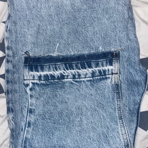 Blå flared jeans med slitna detaljer - Snygga flared blå jeans med slitna detaljer och en klassisk femficksdesign. Perfekta för en avslappnad stil med en touch av edge. De har en rak passform och är tillverkade i ett robust denimtyg. Perfekt storlek som sitter lite loose o inte för baggy. Passar bra till många outfits.