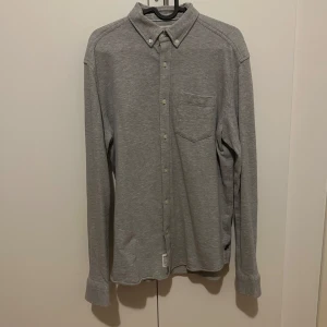 Grå skjorta från Esprit - Snygg grå långärmad skjorta från Esprit med klassisk krage och knappar. Perfekt för en stilren look. Skjortan har en bröstficka och är i en bekväm passform. Skick 9/10 användn nån gång.