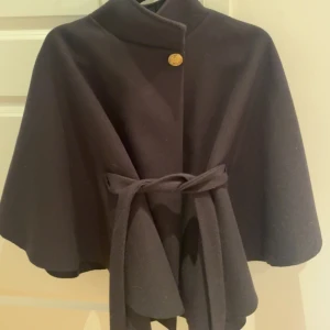 Svart kappa med band - Snygg svart kappa med knytband i midjan. Ser exakt ut som missay kappan fast är från ett annat märke och köpt på hem och trend, knappt använd så väldigt bra skick.