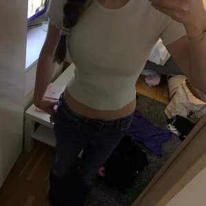 Vit ribbad topp från Gina Tricot - Säljer en stilren vit ribbad topp från Gina Tricot. Toppen har en tight passform och korta ärmar, perfekt för en enkel och snygg look. Den är gjord i ett mjukt och strechigt material.