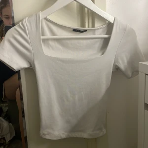Vit kortärmad topp från Amisu - Säljer en stilren vit topp från Amisu med korta ärmar och fyrkantig halsringning. Perfekt för en enkel och snygg look. Passar bra till både jeans och kjol. (Croptopp)
