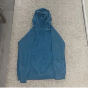 Blå stickad hoodie - Säljer en snygg blå stickad hoodie med långa ärmar och justerbar huva. Perfekt för kyliga dagar med ribbade muddar vid ärmslut och nederkant. Enkelt att matcha med olika outfits.tvör fet men när vi köpte in den så insåg vi att vi hade kollat fel på storleken så den var för liten den är mellan 168-171cm 😉👍✅🦸‍♂️