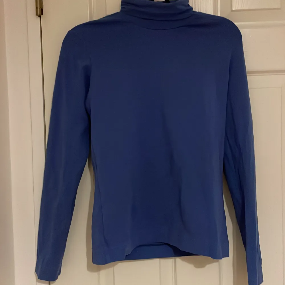 Säljer en stilren blå polotröja med långa ärmar. Perfekt för kyligare dagar och enkel att matcha med olika outfits. Tröjan har en klassisk design med en hög krage. STRLK 146-152. Sydd . Neuletakit & Villapaidat.