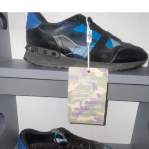 Valentino Rockrunner i svart och blått - Snygga Valentino Rockrunner sneakers i svart och blått med ett coolt camouflage-mönster. Skorna har snörning och är perfekta för en trendig look.
