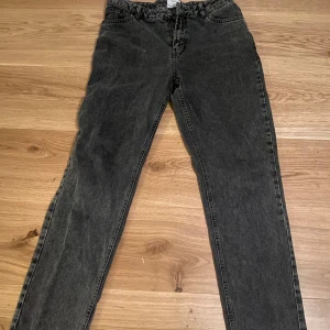 Svarta jeans från Grunt - Snygga svarta jeans från Grunt i en klassisk straight fit. De har en midwaist design och är tillverkade i ekologiskt material. Perfekta för en stilren look med fem fickor och knappgylf.