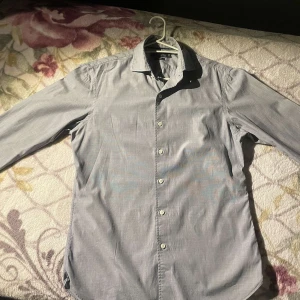 Grå skjorta från Polo Ralph Lauren - Snygg grå skjorta från Polo Ralph Lauren i slim fit. Tillverkad i stretchig poplin med klassisk krage och knappar framtill. Perfekt för en stilren look. Helt äkta, inga fel på den, säljer för jag är för lång för den (193) riktigt fint sommarplagg