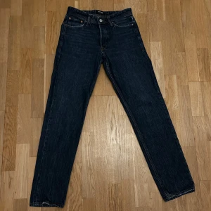 Mörkblå jeans från Jack & Jones - Snygga mörkblå jeans från Jack & Jones loose fit. Klassisk design med fem fickor och knappgylf. Perfekta för en avslappnad stil.