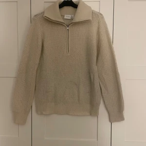 Beige stickad tröja från Vila  - Säljer en stilren beige stickad half zip tröja från Vila. Tröjan har långa ärmar och en ribbad struktur. Använd men är i gott skick! 💖