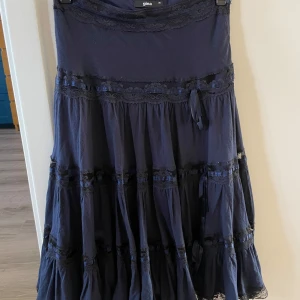 Mörkblå kjol från Gina - En mörkblå lång kjol från Gina tricot i storlek 36. Kjolen har vackra spetsdetaljer. Lite slitage på spetsen men inte synligt om man inte synar noggrant. Annars i fint skick. 