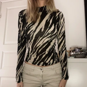 Zebra mönstrad långärmad topp/tröja i storlek S (Stockholm stil) - Sjukt snygg långärmad formgivande zebra mönstrad topp. Kort rundad turtleneck, passar perfekt till lågmidjade jeans. Storlek S och i fint skick 🤍🦓