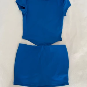 Set  - Kornblått sett, tröjan är öppen i ryggen och kjolen har shorts inbyggt! 