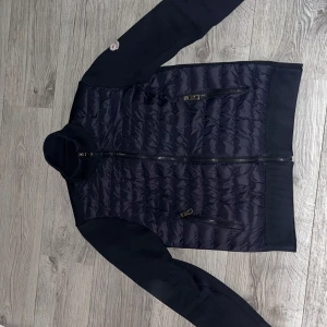 Moncler cardigan  - Säljer en snygg marin blå Moncler cardigan i utmärkt skick! Jackan är sparsamt använd och har haft den i mindre än 1 år. Den har legat i garderoben för det mesta. Pris kan diskuteras vid snabbaffär.