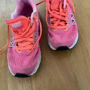 Rosa Nike sneakers - Säljer ett par snygga och bekväma rosa Nike sneakers i storlek 40. Skorna har en fräsch och sportig design med snörning och vit sula. Perfekta för träning eller en aktiv vardag. De är i bra skick och redo för nya äventyr! Pris kan diskuteras!