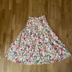  kjol från Gina Tricot - Superfin blommig kjol från Gina Tricot i storlek 36. Kjolen har ett härligt mönster i rosa, grönt och beige med volanger som ger en romantisk känsla. 