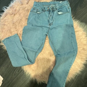 Blå jeans - Säljer ett par klassiska blå jeans i en petite boyfriend passform. De har en hög midja och är perfekta för vardagsbruk. Jeansen är i bra skick och har en snygg, enkel design med fickor fram och bak.